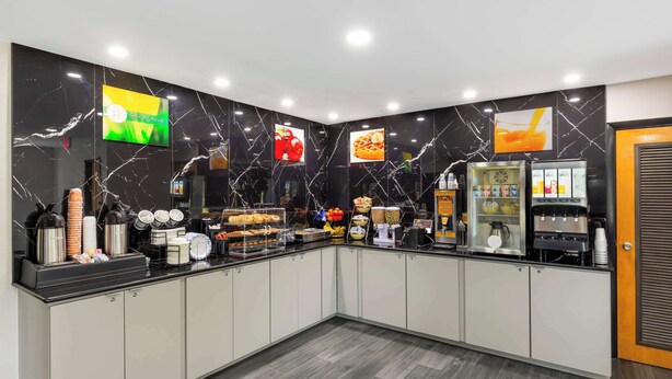 A modern kitchen area with marble backsplash, a coffee station, and a juice dispenser. - Quality Inn Washington NC (Washington)