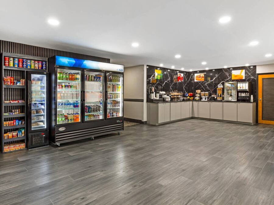 A modern hotel lobby with a vending machine, a refrigerator, and a counter with a marble backsplash.
