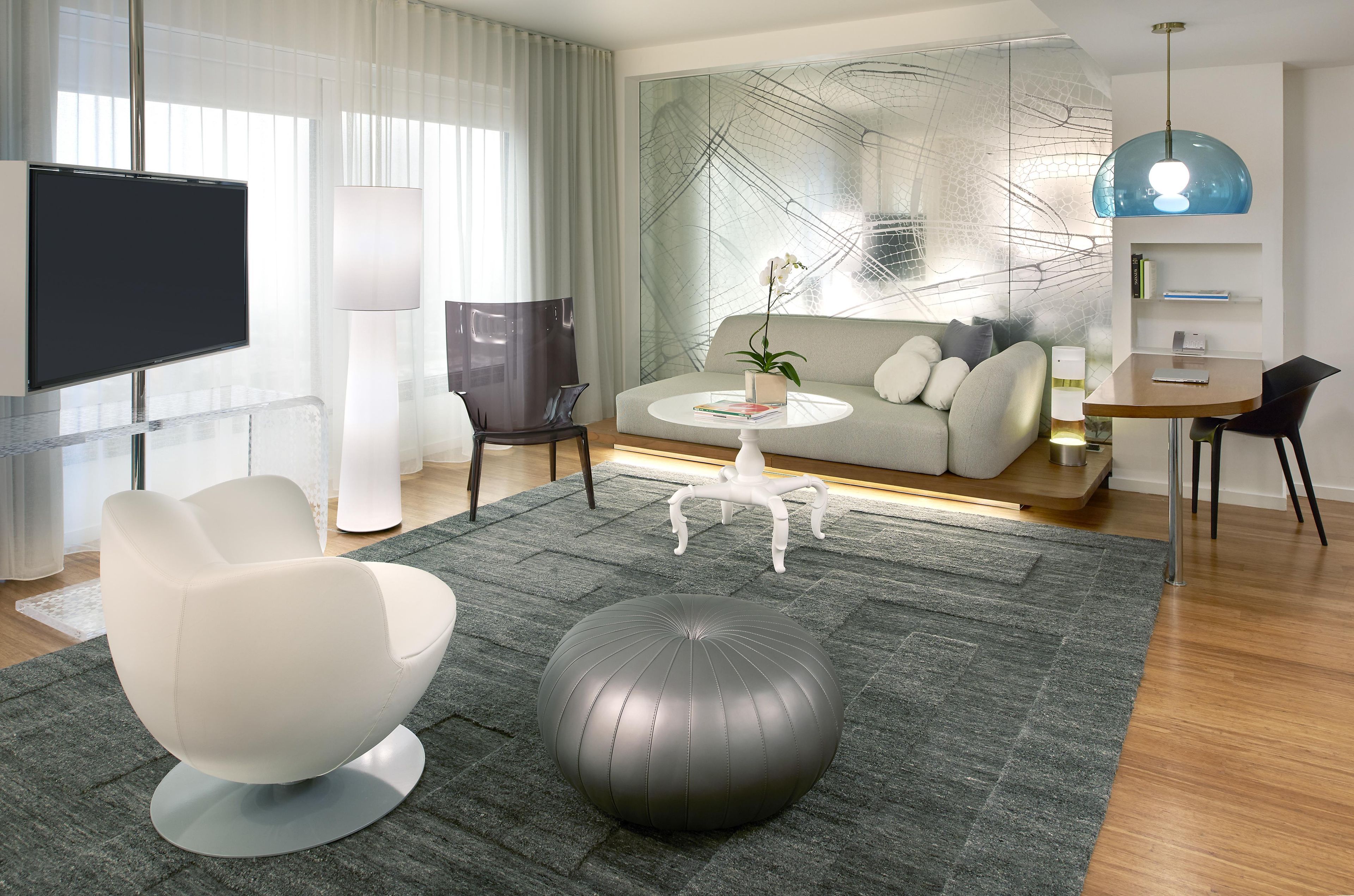 Een moderne woonkamer met een flatscreen televisie, een bank, een salontafel en een decoratieve plant.