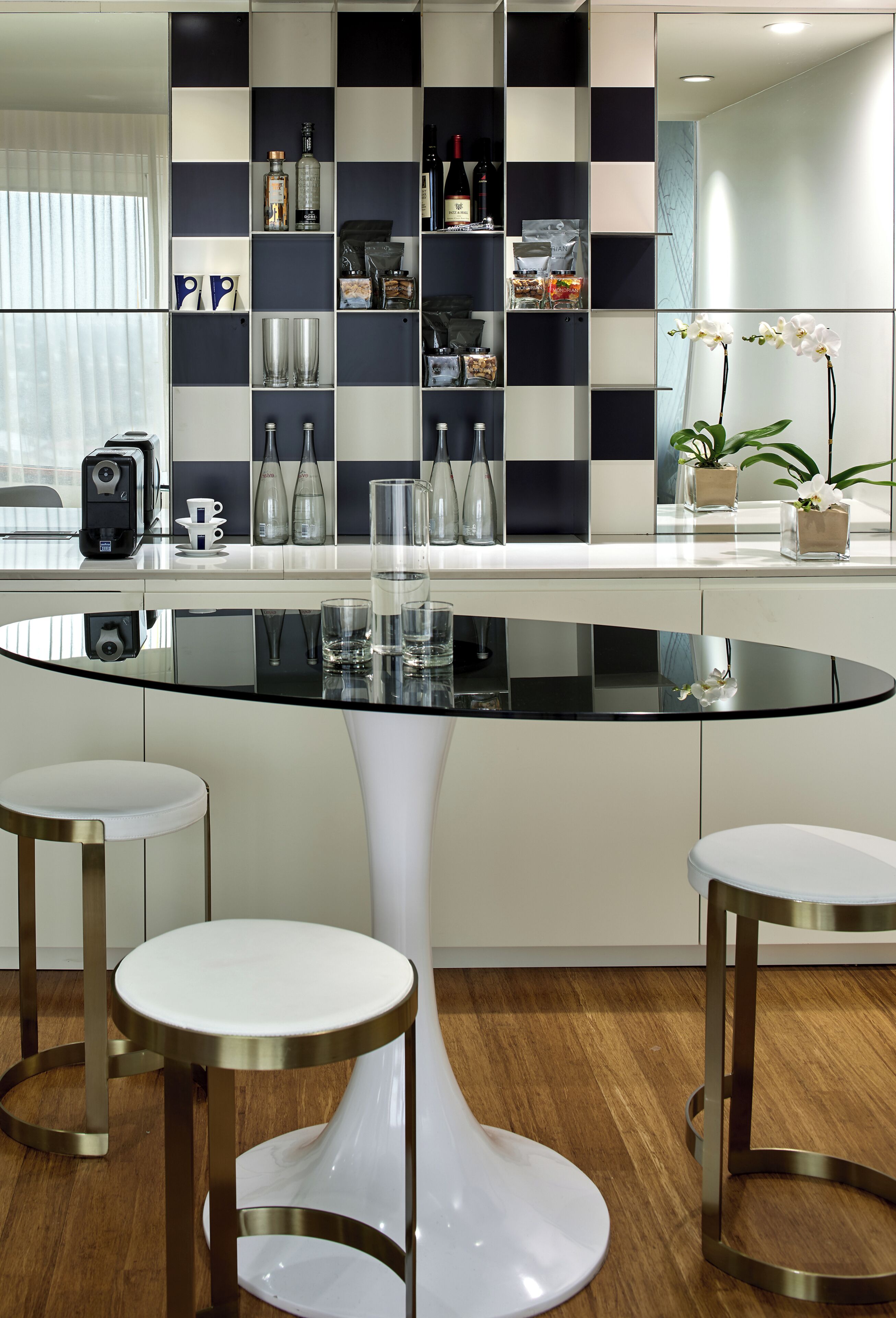 A modern kitchen with a central island, bar stools, and a checkered backsplash.