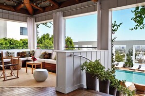 A balcony with a pool, seating area, and potted plants. - The Valorian West Hollywood, Curio Collection by Hilton (West Hollywood)