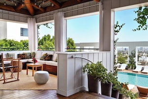 A balcony with a pool, seating area, and potted plants.
