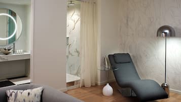 A modern bathroom with a shower, a glass-enclosed vanity, a massage chair, and a floor lamp.