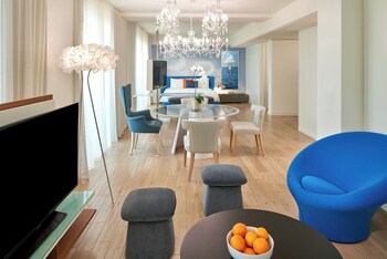 A dining area with a glass table, white chairs, a chandelier, and a city view. at The Valorian Los Angeles, Curio Collection by Hilton