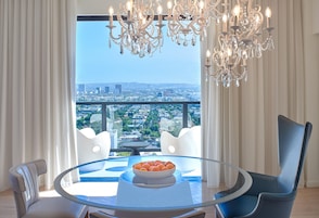 A modern dining area with a glass table, white chairs, and a chandelier.