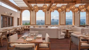 A restaurant with a wooden interior, large windows, and hanging light fixtures.