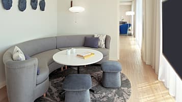 A modern living room with a grey sofa, round coffee table, and ottomans, a white lamp, and abstract wall art.