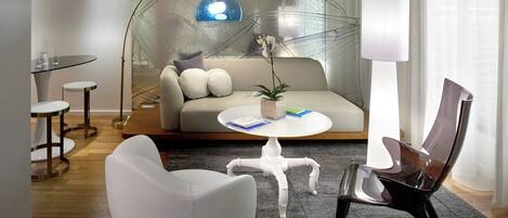 A modern living room with a glass table, white sofa, and a potted plant.