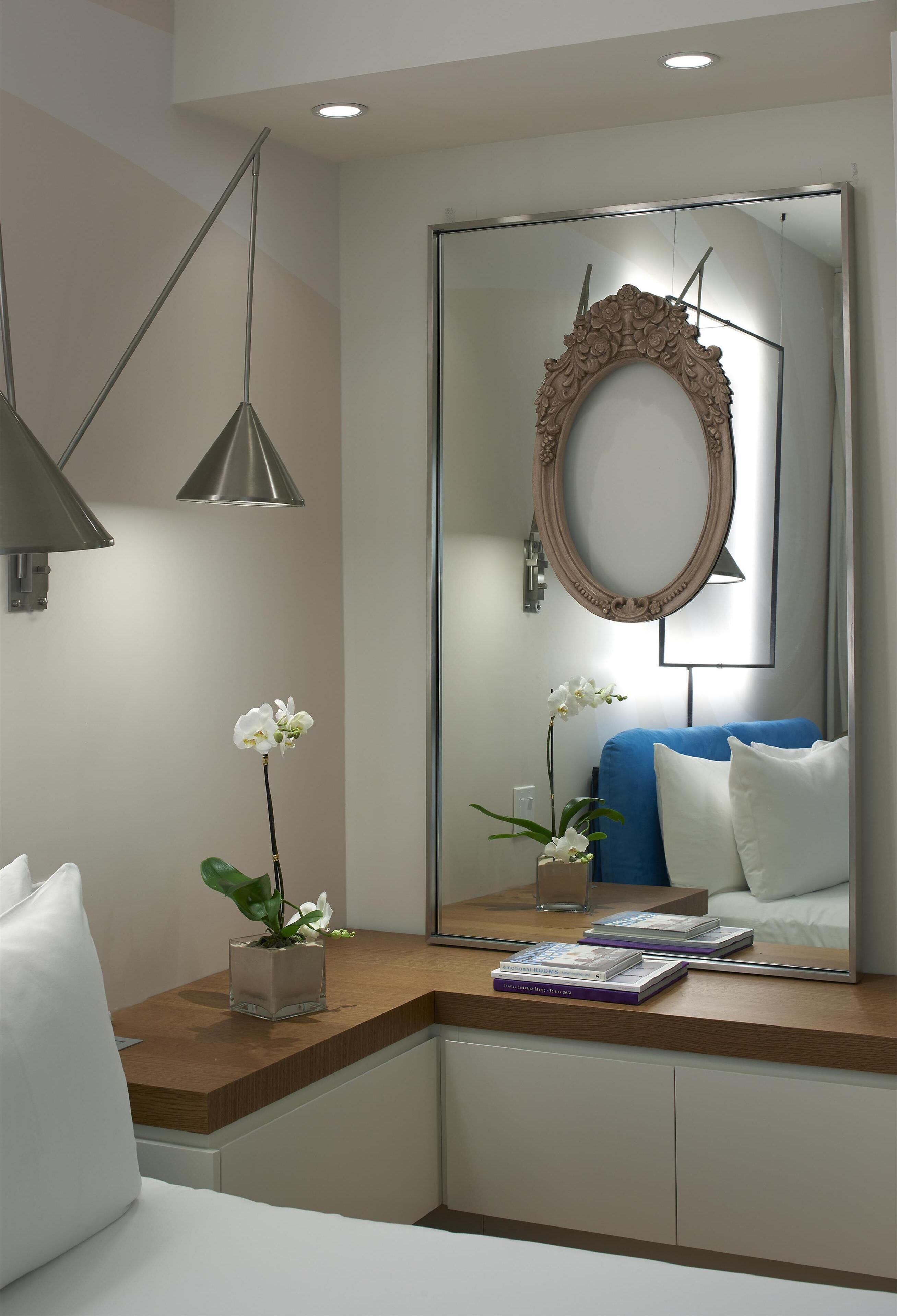 Une chambre à coucher moderne, comprenant un lit, une table de chevet, une lampe, un miroir et des plantes décoratives.