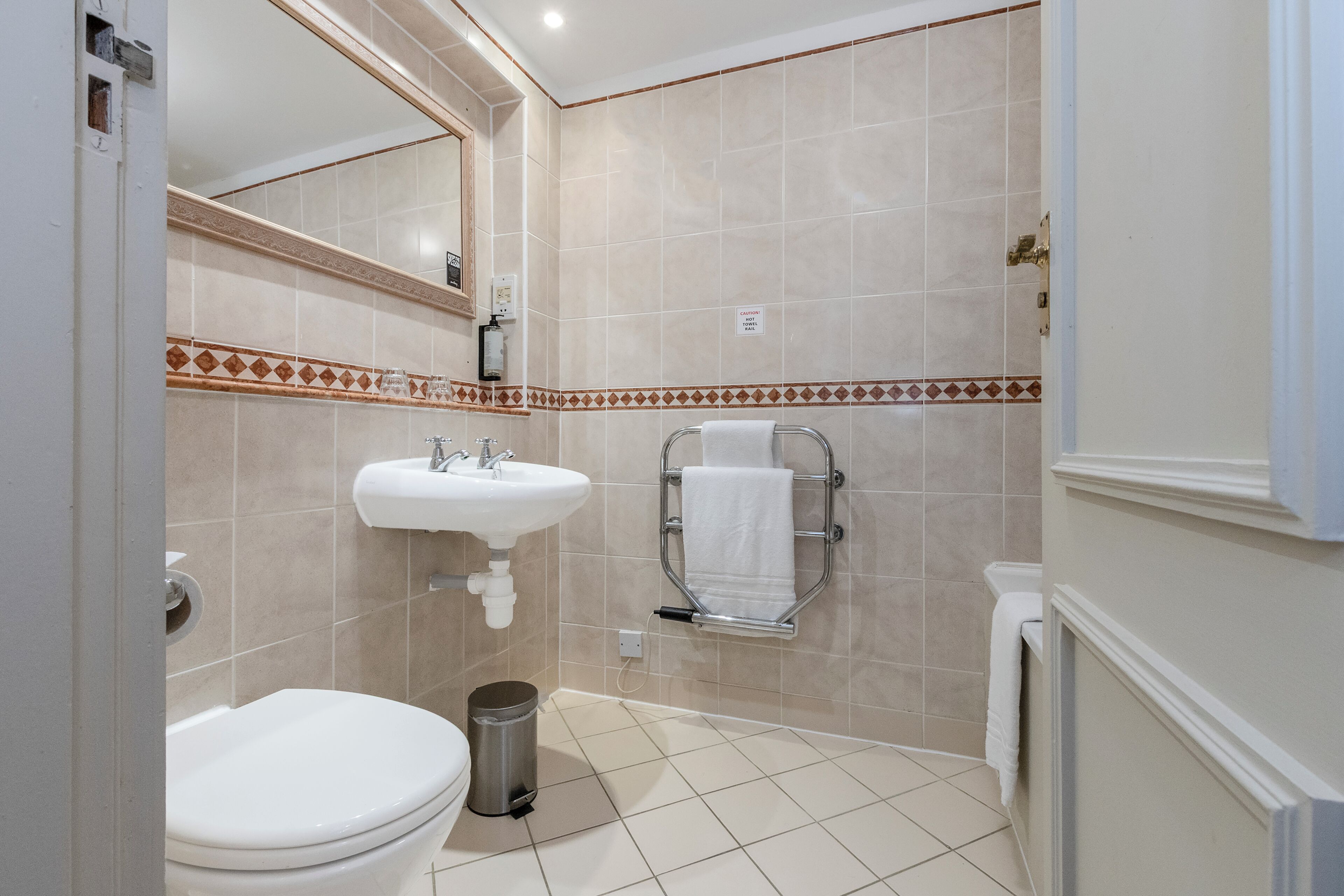 A bathroom with a toilet, sink, and towel rack.
