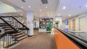 Eine Hotelhalle mit Treppe, Weihnachtsbaum und einer Wand mit farbenfrohen Kunstwerken.