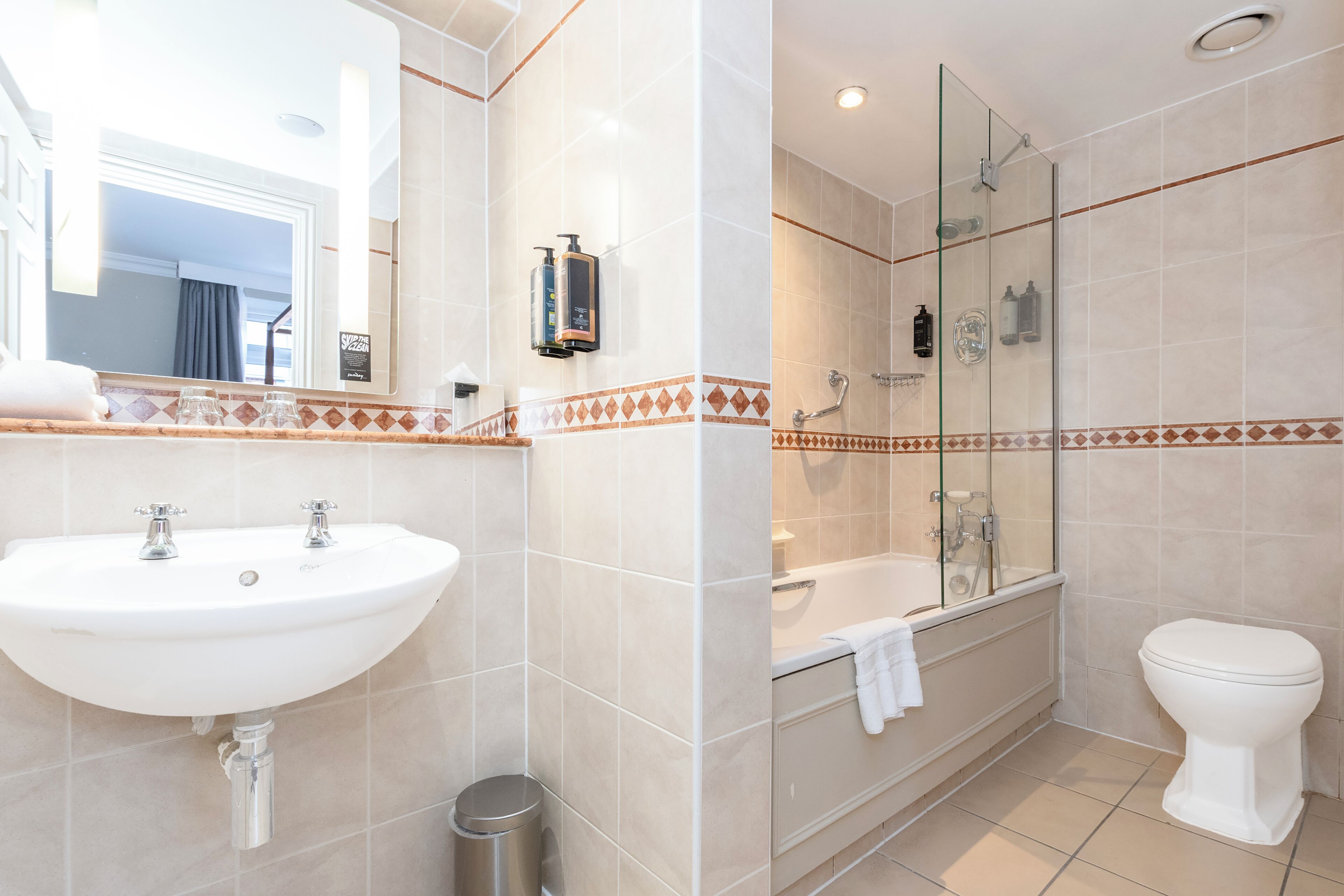 A modern bathroom with a sink, mirror, shower, and toilet.