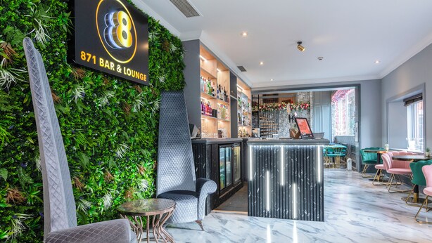 Eine Bar mit einer grünen Wand, einer Bar und Sitzgelegenheiten.
