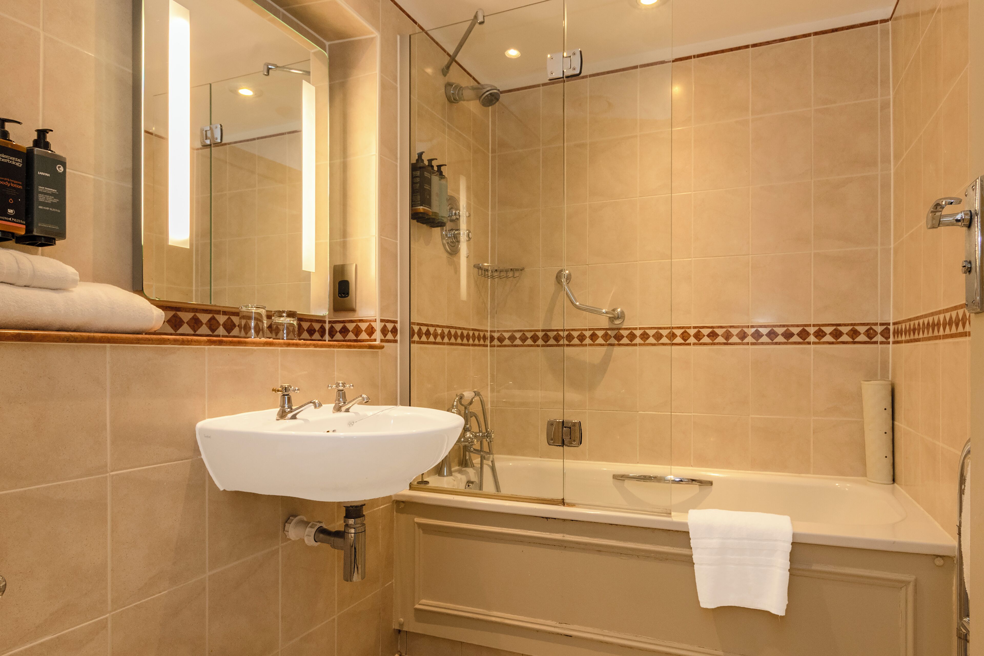 A bathroom with a sink, mirror, shower, and bathtub.