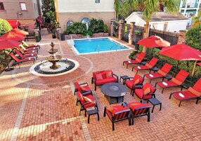Zona de piscina con sillas de descanso y sombrillas, una fuente y un pozo de fuego.