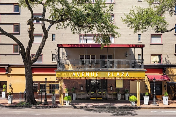 Un edificio con un letrero que dice 'AVENUE PLAZA' y un toldo rojo.