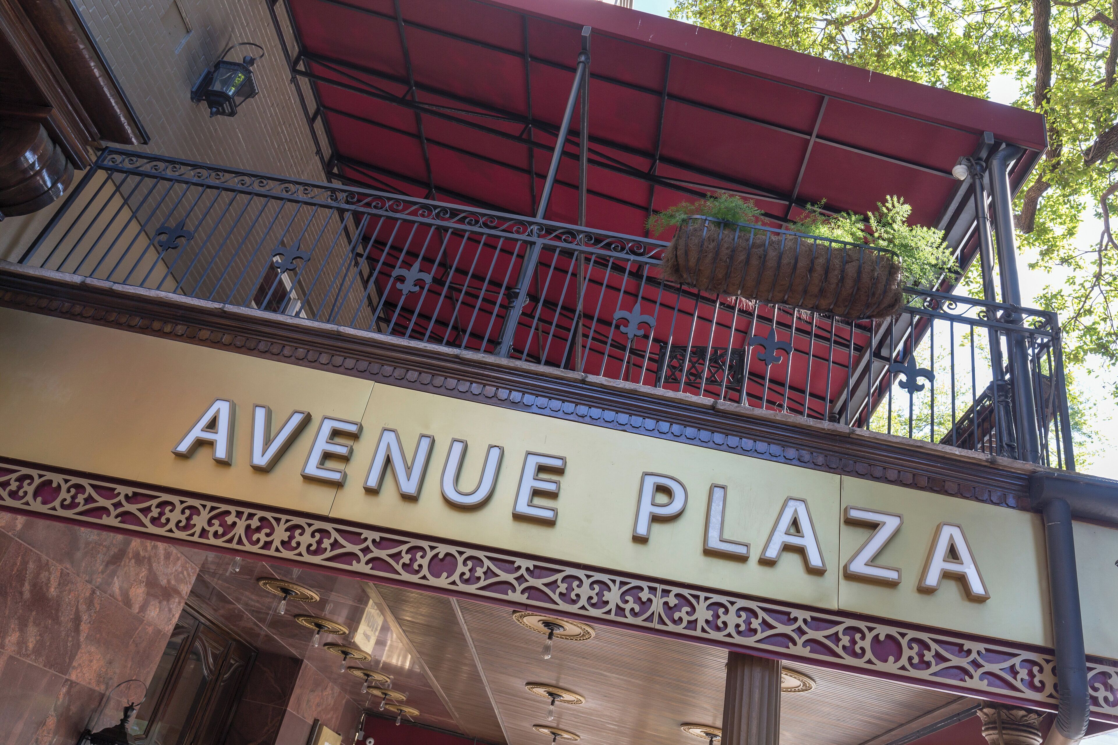 The exterior of the Avenue Plaza building with a balcony and hanging planters.