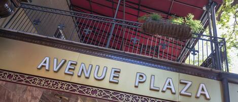 The exterior of the Avenue Plaza building with a balcony and hanging planters.