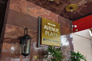 Letrero de bienvenida para Avenue Plaza, parte de Wyndham Vacation Resorts, con un diseño moderno y un fondo de pared de piedra.
