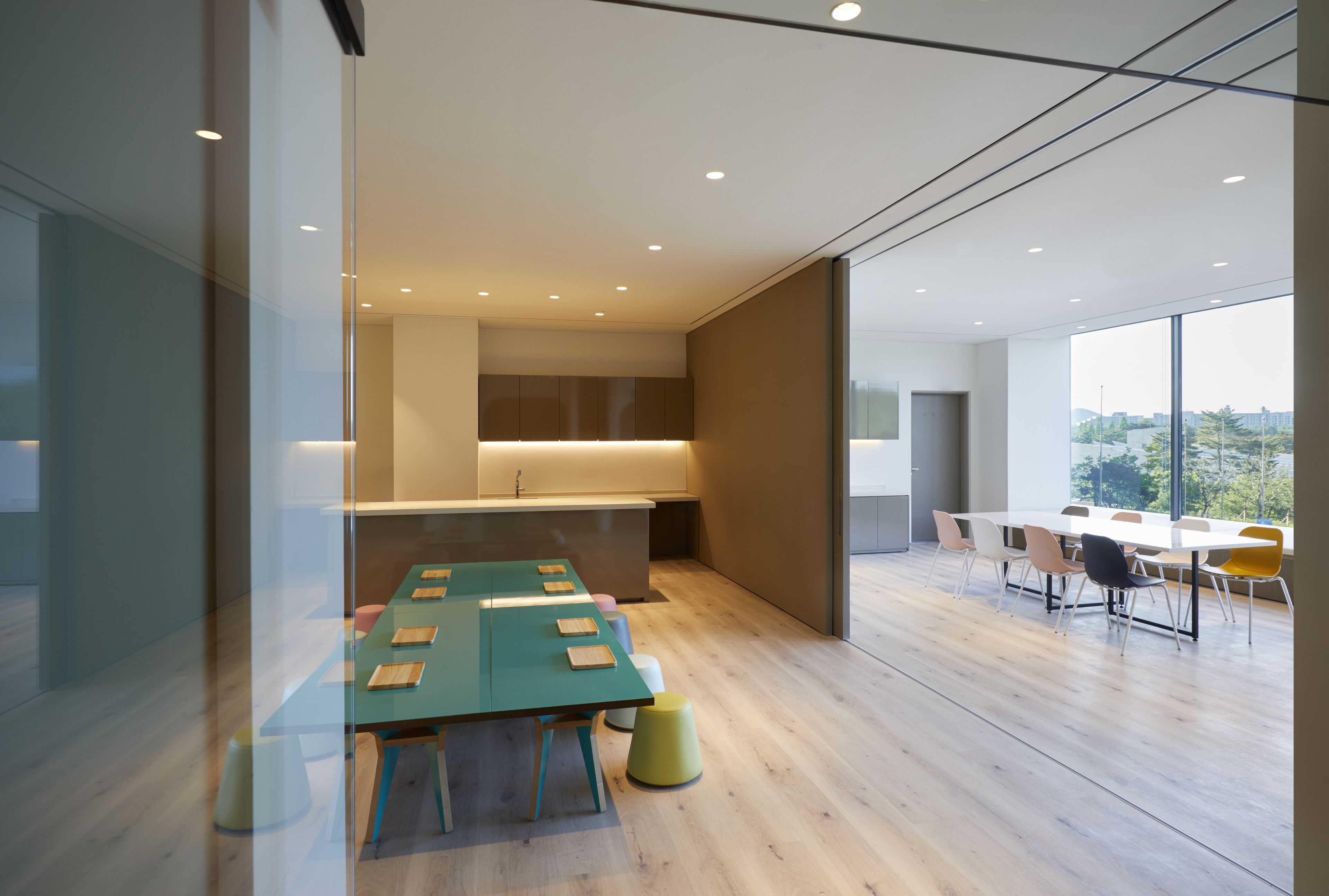 Una sala de reunions moderna amb una taula llarga, cadires i una zona de cuina.