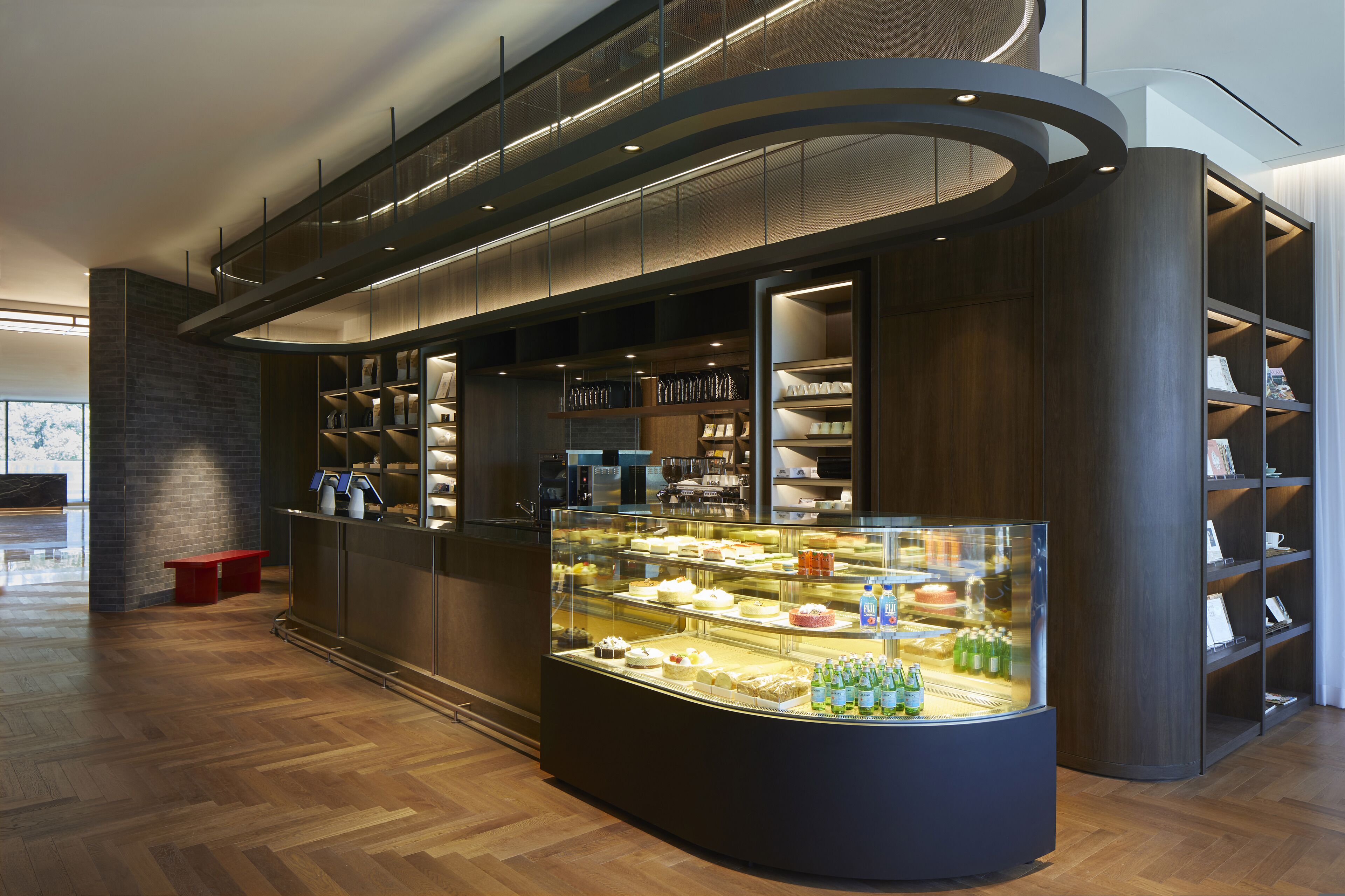 A modern interior with a bakery display, wooden shelving, and a curved counter.