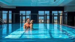 A swimming pool with a city view, large windows, and a skylight.