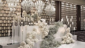 A luxurious interior with chandeliers, white floral arrangements, and candlelit displays.