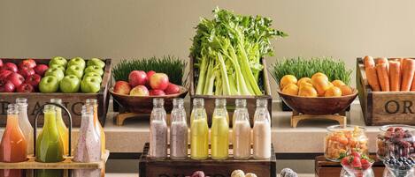 A variety of fresh fruits, vegetables, and beverages displayed on wooden crates and shelves.