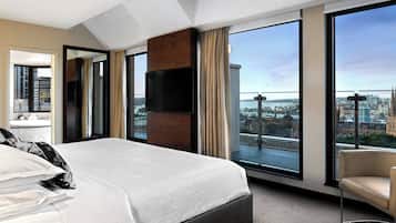 Ein modernes Hotelzimmer mit einem großen Bett, einem Fernseher und einem Balkon mit Blick auf die Stadt.