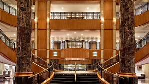 A grand hotel lobby with a central staircase, marble columns, and multiple floors.