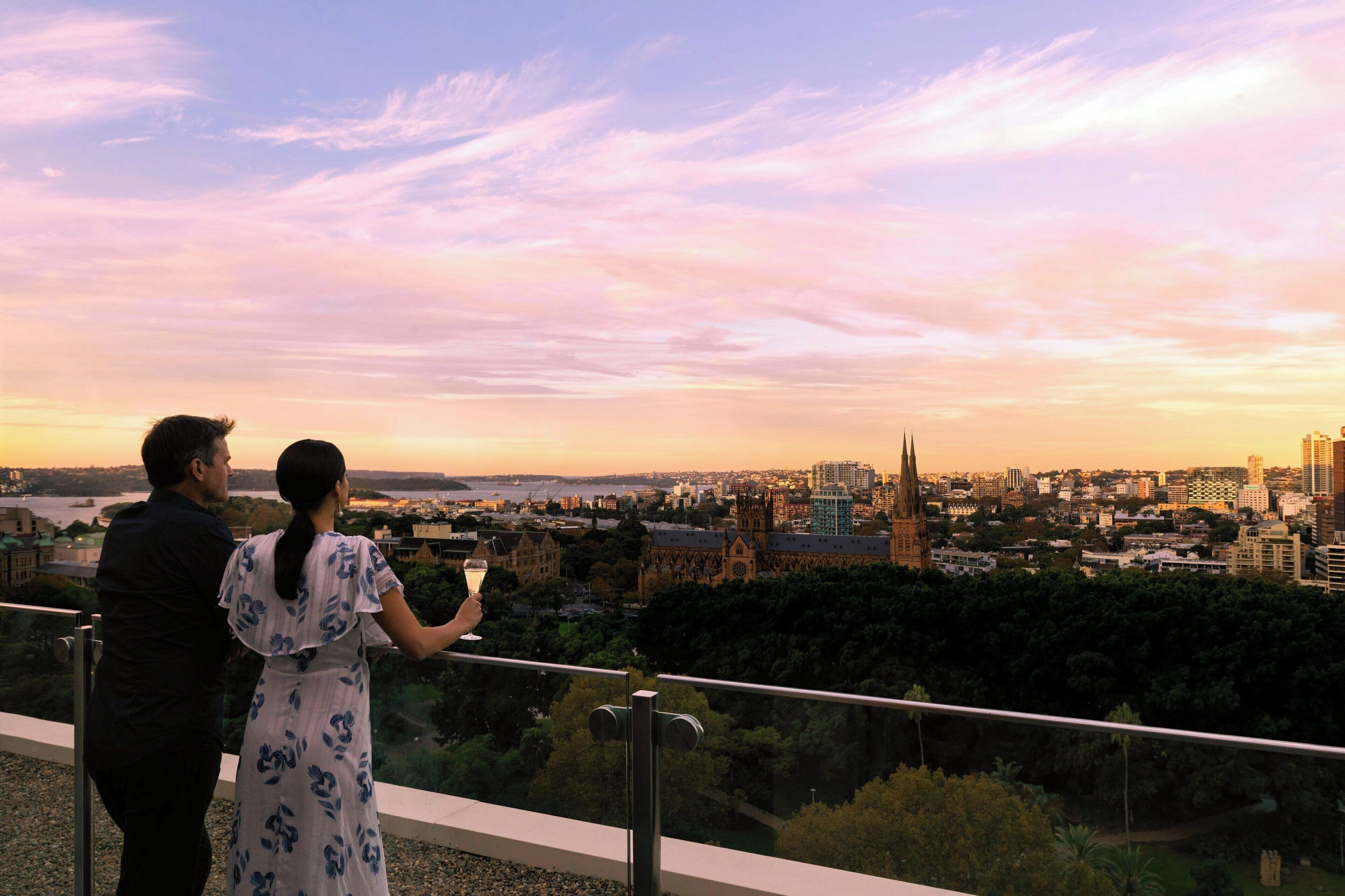 Una pareja contempla un paisaje urbano con un río, edificios históricos y la aguja de una iglesia.