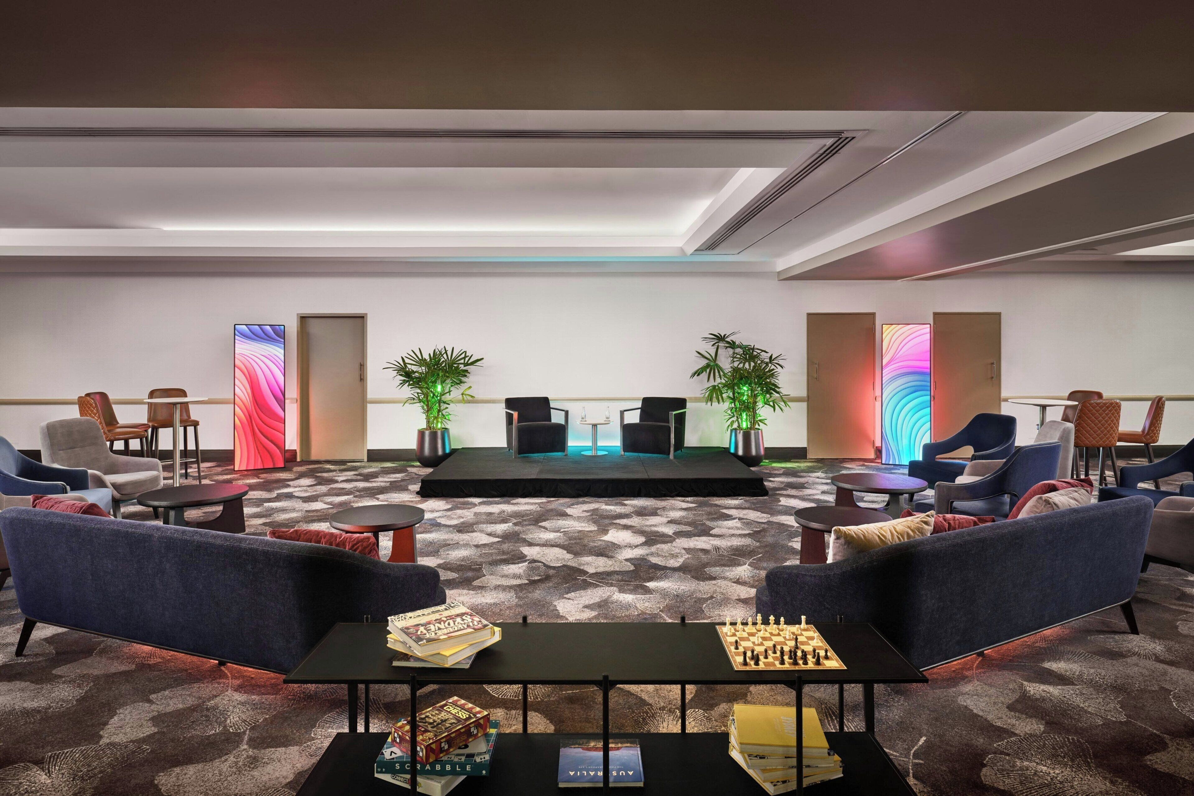 A modern lounge area with sofas, tables, and a stage.