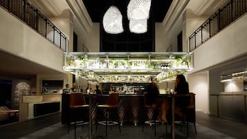 Uma área de bar com teto alto, luminárias pendentes e um balcão com banquetas.