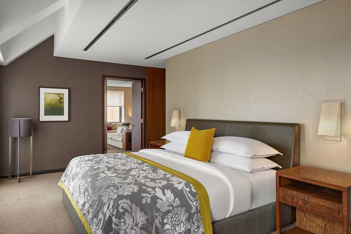 Een hotelkamer met een groot bed, een nachtkastje, een lamp en een ingelijste foto aan de muur.