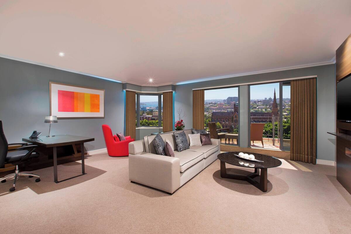 Een moderne woonkamer met een bank, rode fauteuil en een pooltafel.