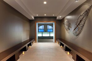 A modern hallway with benches, a reception area, and a decorative wall piece.
