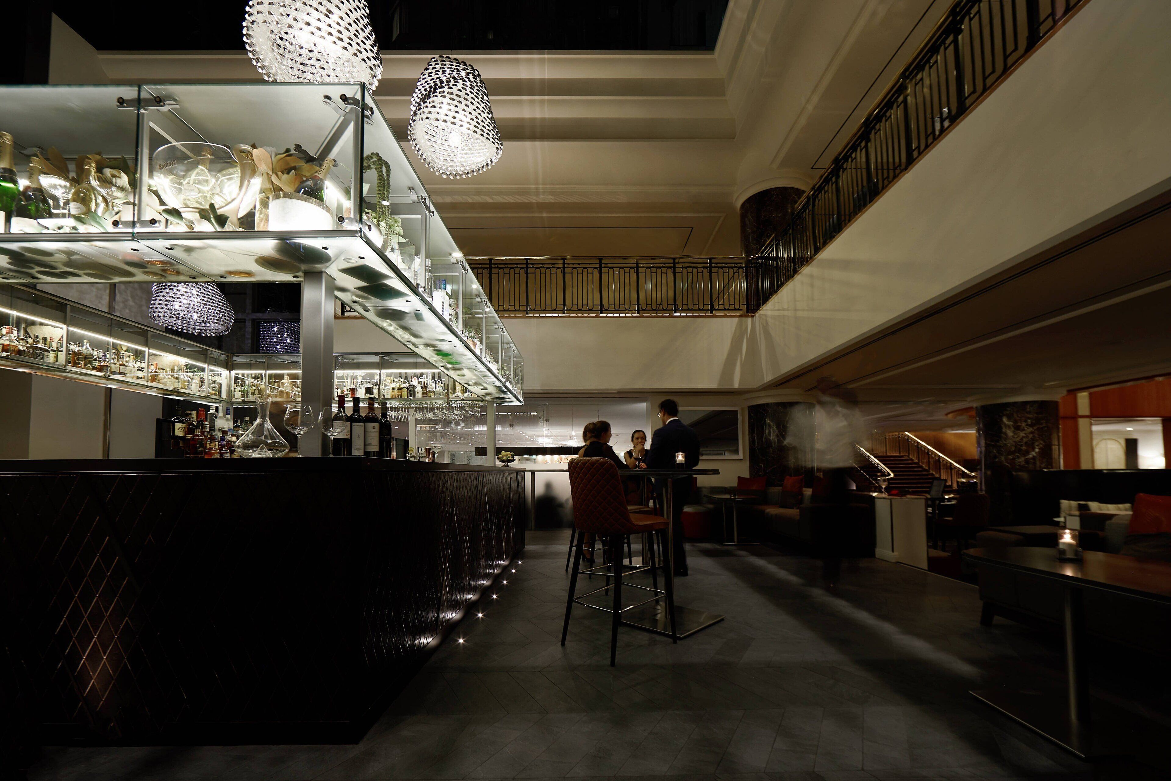 A bar area with a high ceiling, glass display cases, and hanging pendant lights.