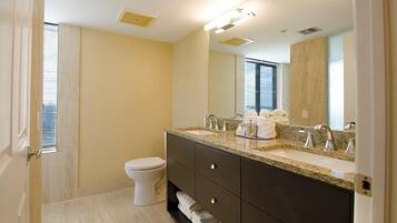 Une salle de bain moderne avec un meuble-lavabo à deux vasques, des toilettes et un grand miroir.