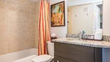 A bathroom with a bathtub, toilet, and shower curtain.