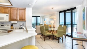 A modern kitchen with a microwave, sink, and dining area with chairs and a glass table.
