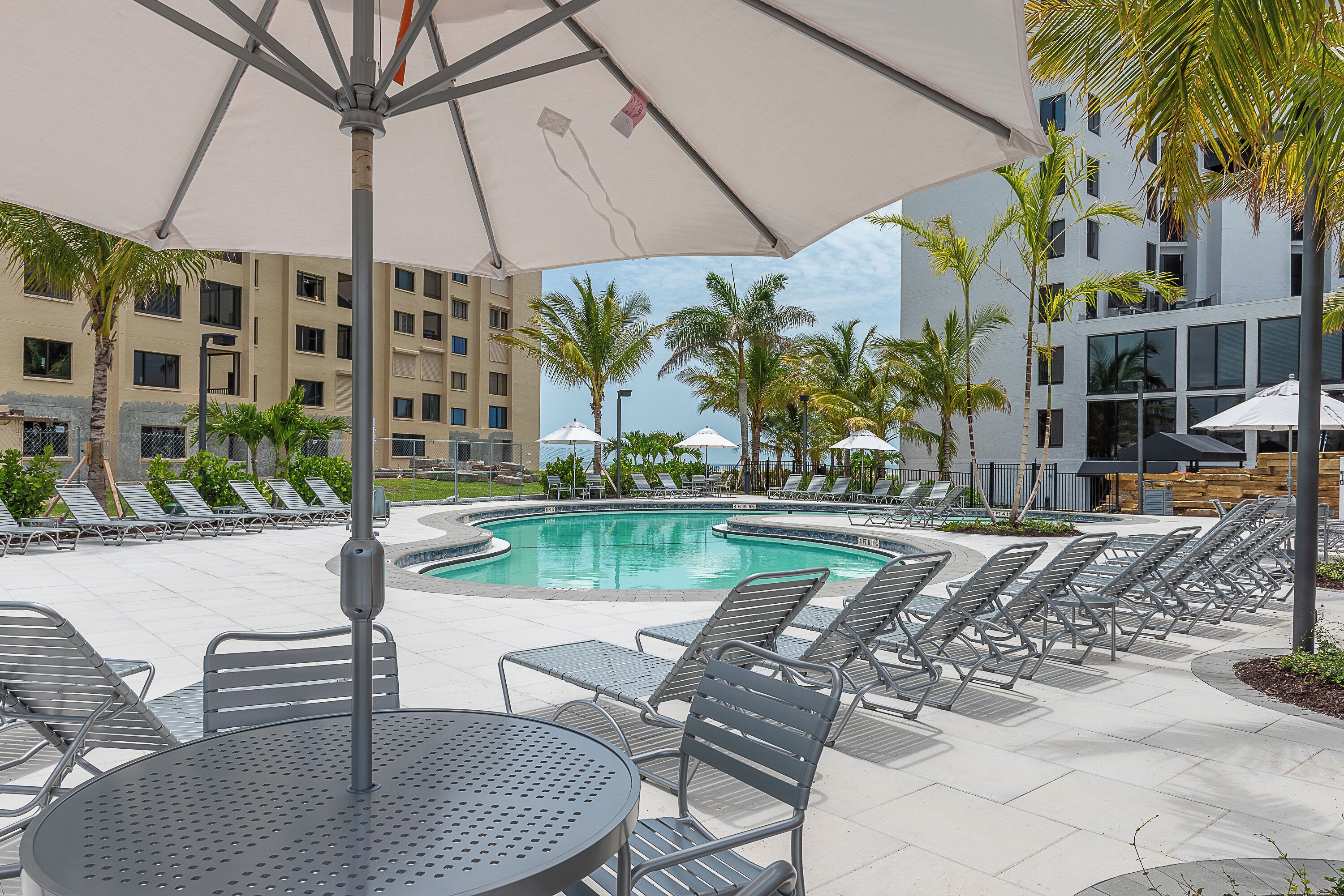 Un espace aménagé au bord de la piscine, avec des chaises longues, une table et des parasols.