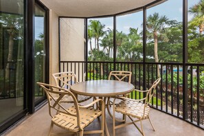 Enjoy a peaceful retreat with a balcony overlooking a serene garden, featuring a round table and comfortable seating for four.