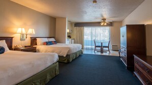 Une chambre d’hôtel avec deux lits, un bureau, une chaise, une armoire et une vue sur l’extérieur.