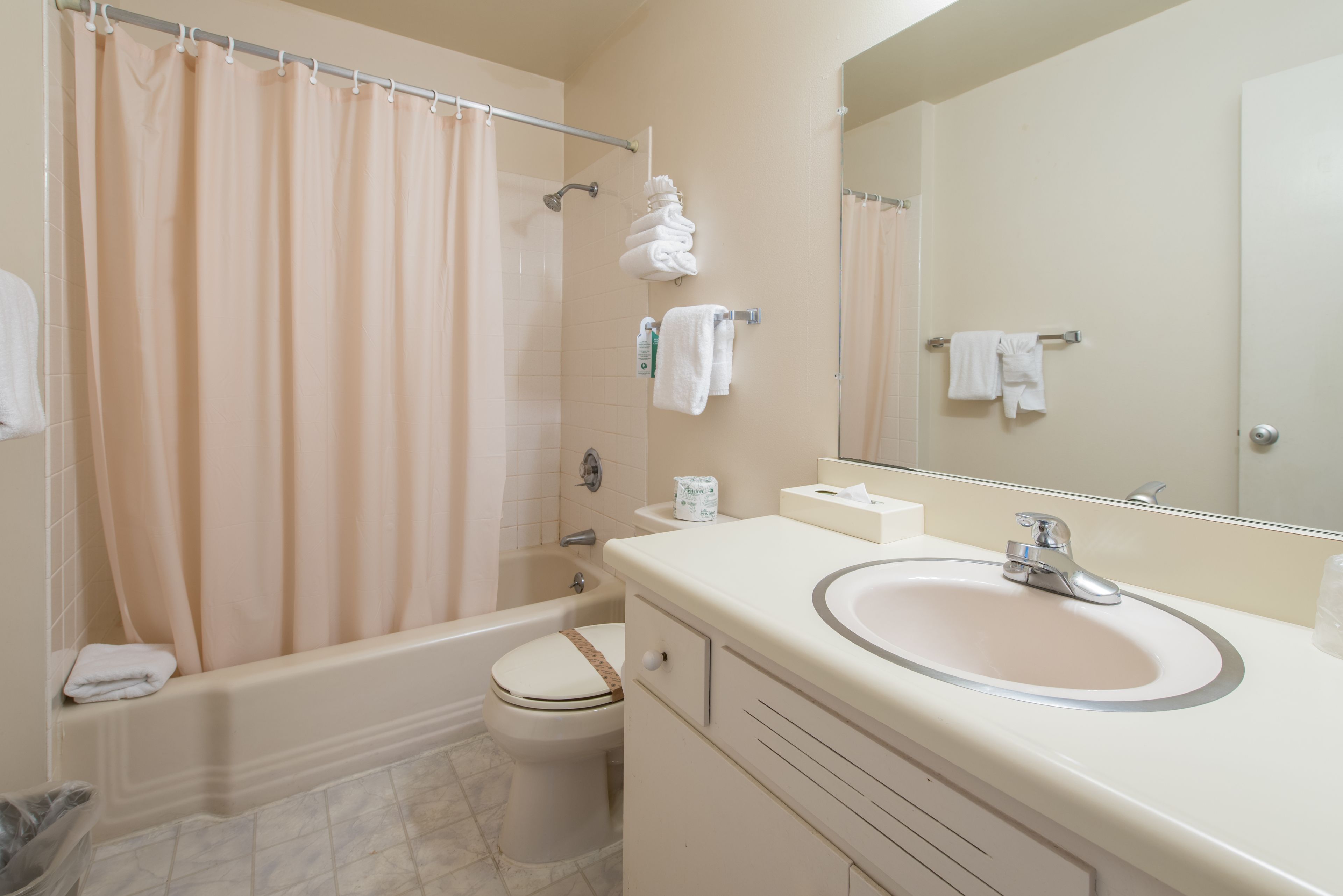 A bathroom with a bathtub, toilet, sink, and a mirror.