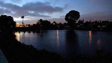 A nighttime view of a lake with reflections of lights, trees, and distant buildings.