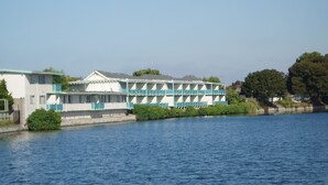 Un hôtel situé au bord de l’eau, doté d’une rangée de balcons et d’un espace piscine.