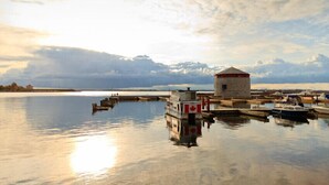 Un rivage paisible avec un petit quai et un bâtiment doté d’un toit rouge.