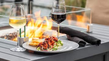 Una mesa de comedor con una copa de vino blanco, una copa de vino tinto y pollo a la parrilla en un plato.