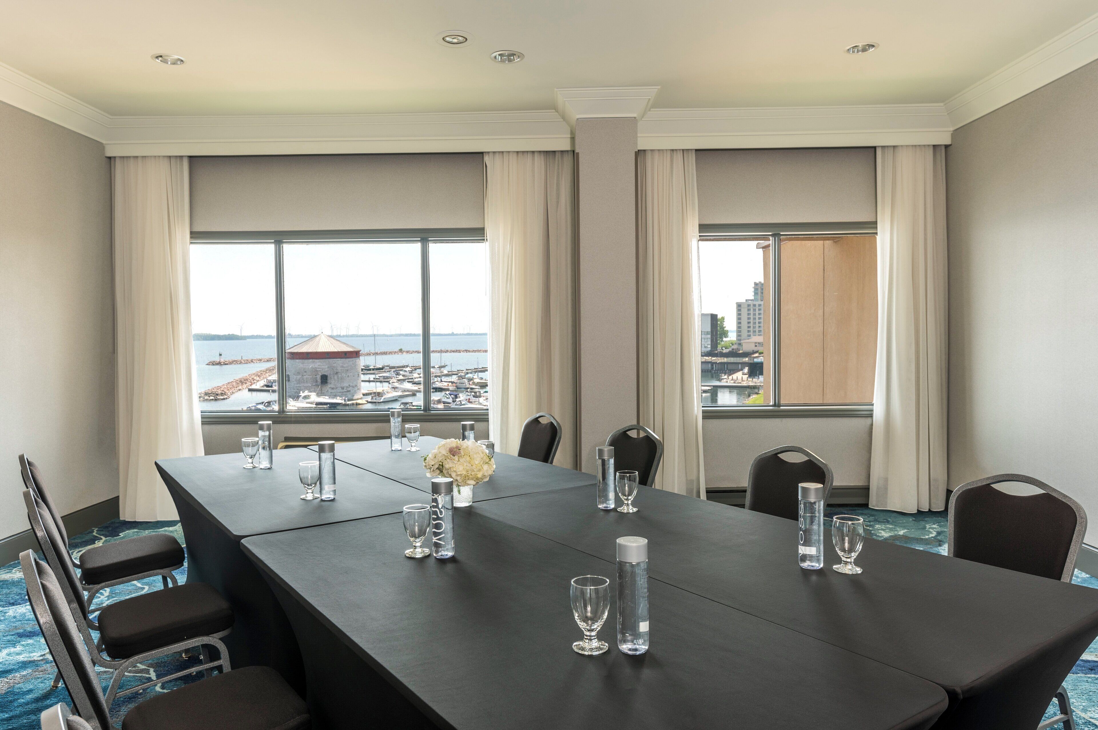 A conference room with a long table, chairs, and a view of the city through large windows.