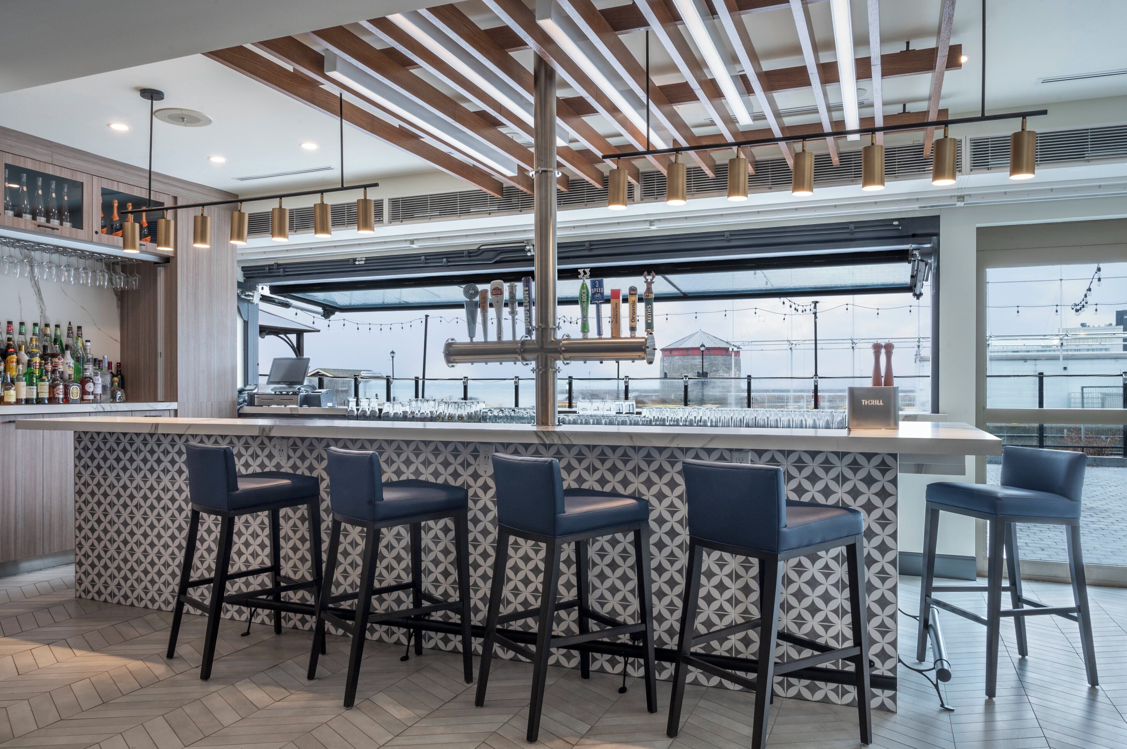 A bar area with a high counter, multiple stools, and a view of the city through large windows.